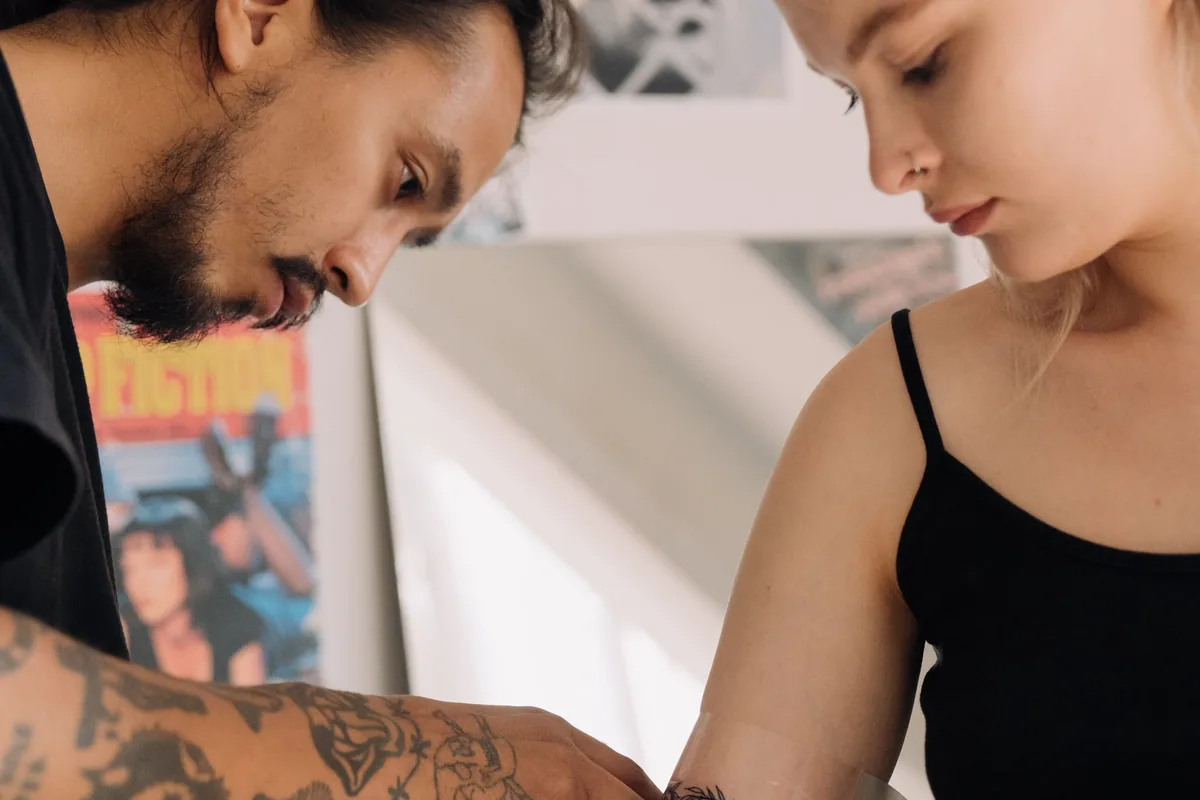Tattoo artist wrapping a client's fresh arm tattoo