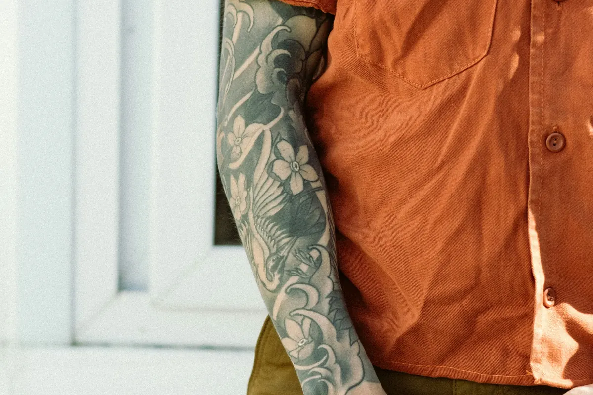 Black and grey sleeve on a man's arm, the kind of large project behind a sleeve tattoo price in the thousands