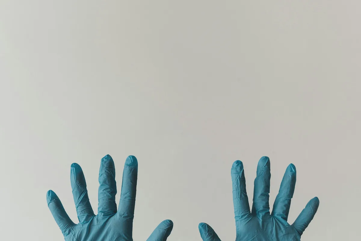 Pair of hands in blue nitrile gloves, as worn by clinic staff before tattoo removal in Johor Bahru