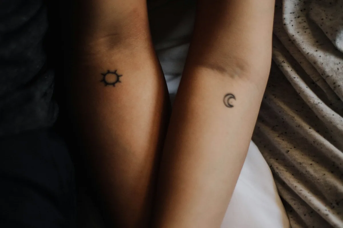 Couple holding hands with matching sun and moon couple tattoos on their wrists
