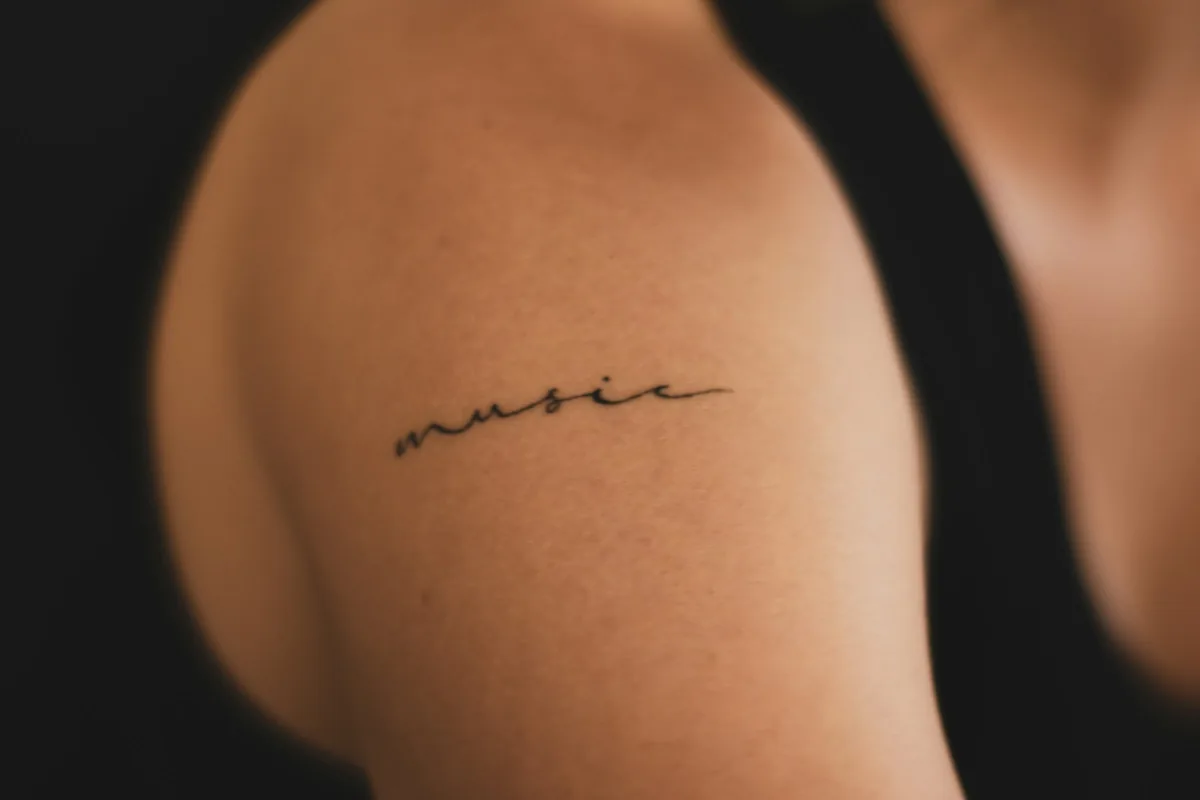 Fine line script tattoo on a shoulder, one of many small tattoo ideas