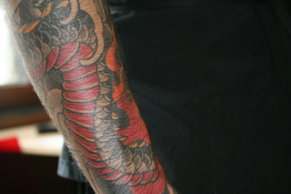 Close-up of a colourful Japanese-style dragon tattoo on an arm