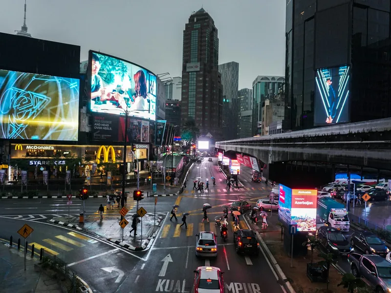Rainy evening traffic and billboards in central Kuala Lumpur, where many visitors book a tattoo in Malaysia as a tourist