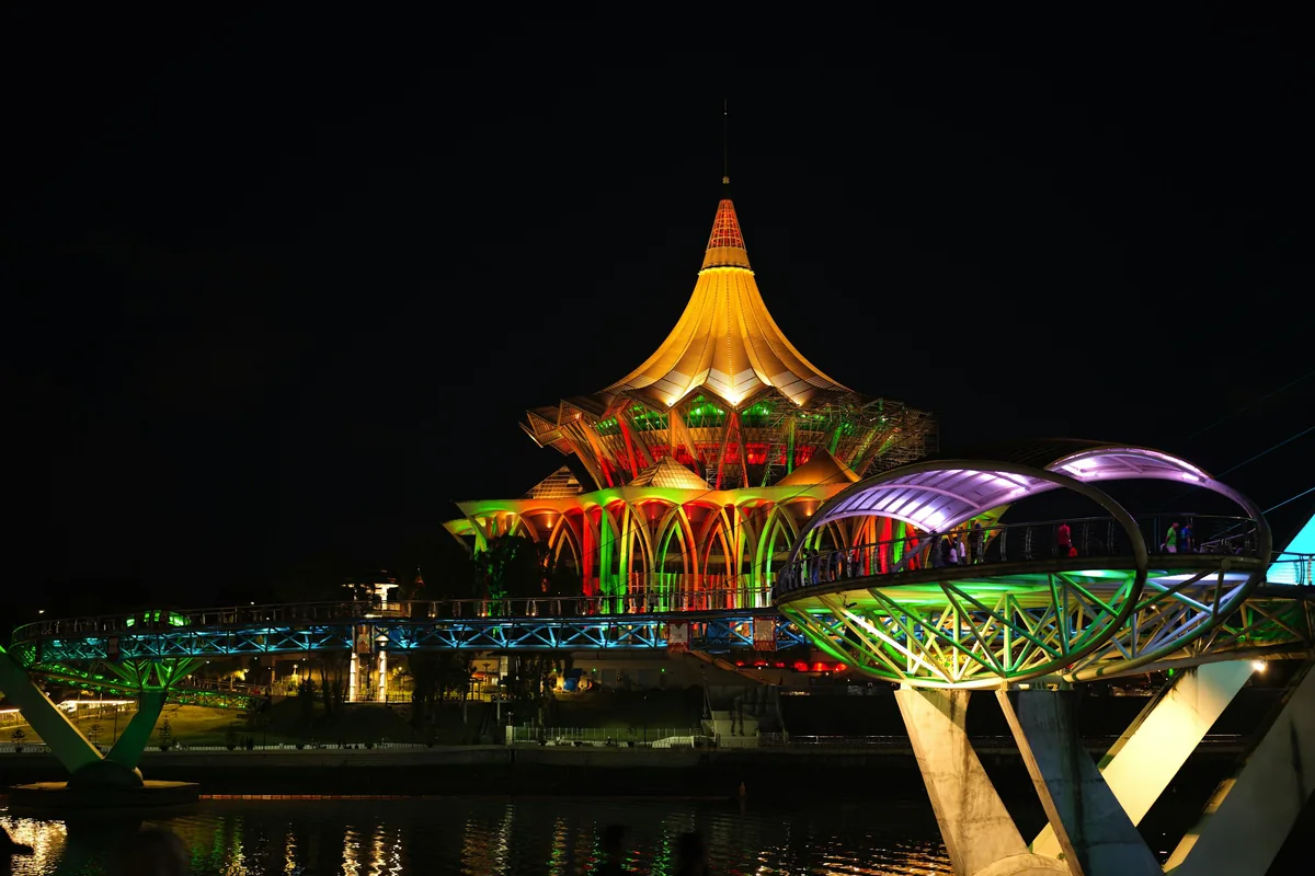 Sarawak State Legislative Assembly building and Darul Hana Bridge lit up at night in Kuching, home of Sarawak tattoo culture