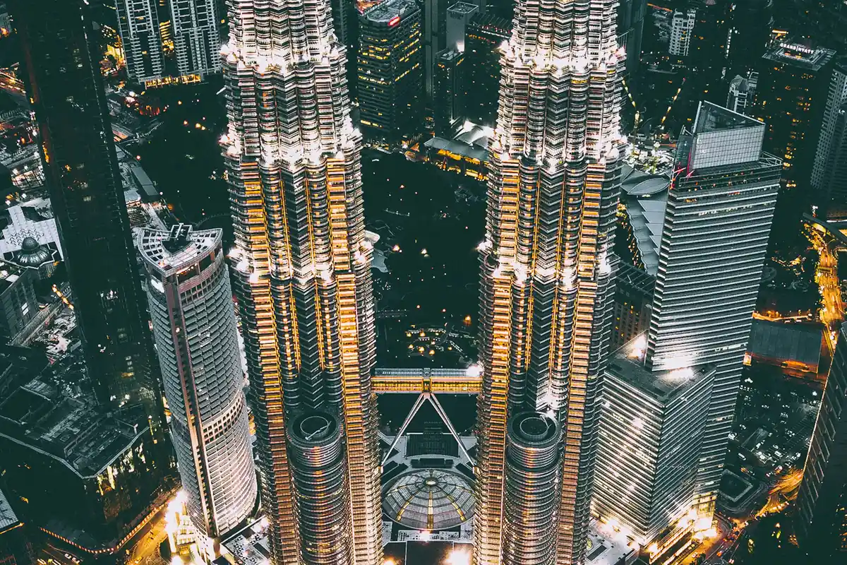 Aerial view of the Petronas Twin Towers lit up at night over Kuala Lumpur, where getting a tattoo is legal in Malaysia for adults