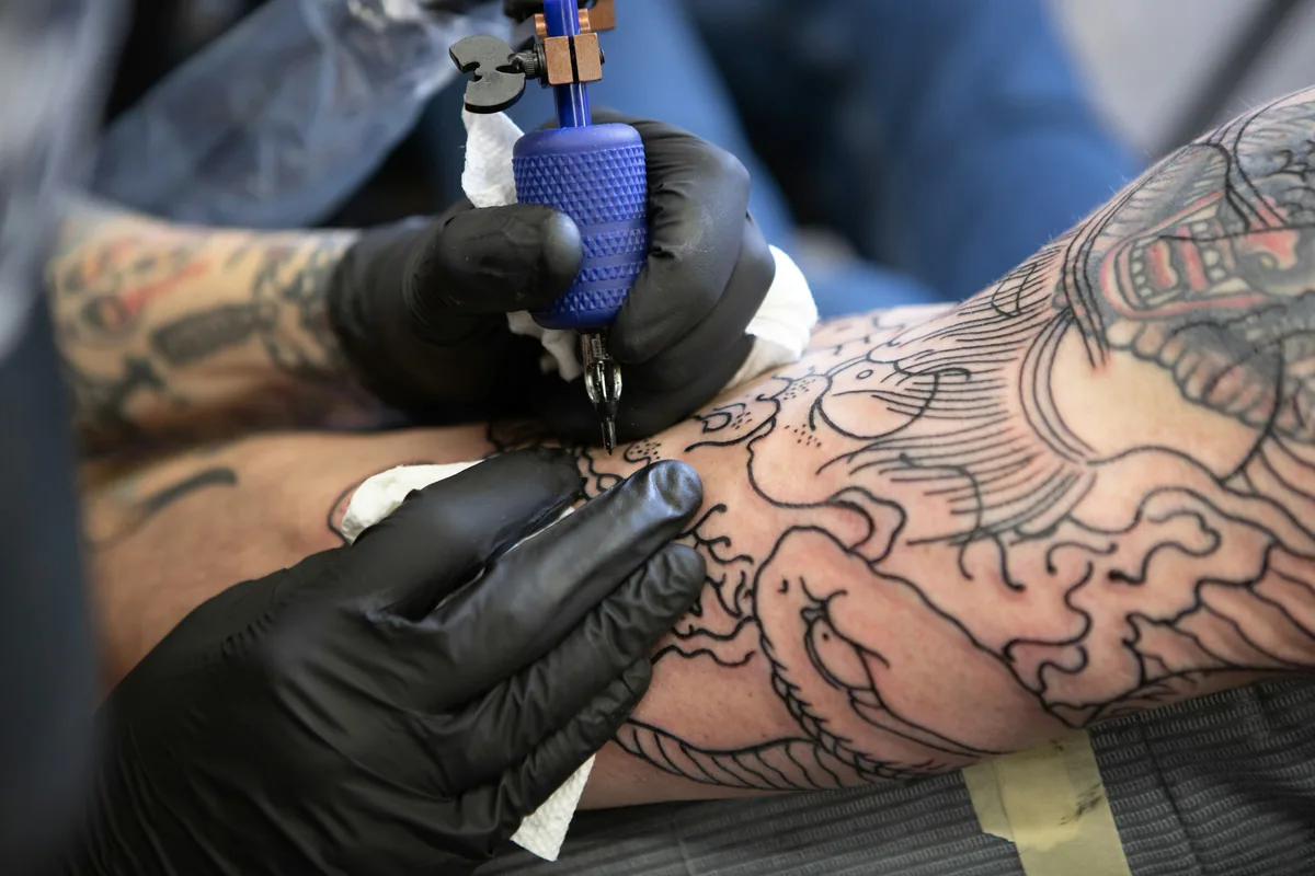 Artist outlining a large sleeve design on a client's arm, the kind of multi-session project that pushes tattoo price in Malaysia into the thousands