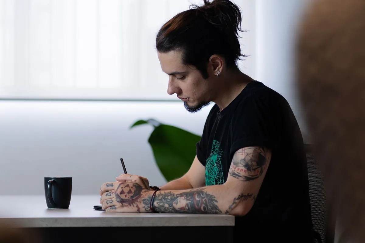 Tattoo artist drawing a first tattoo design at a desk by a bright window