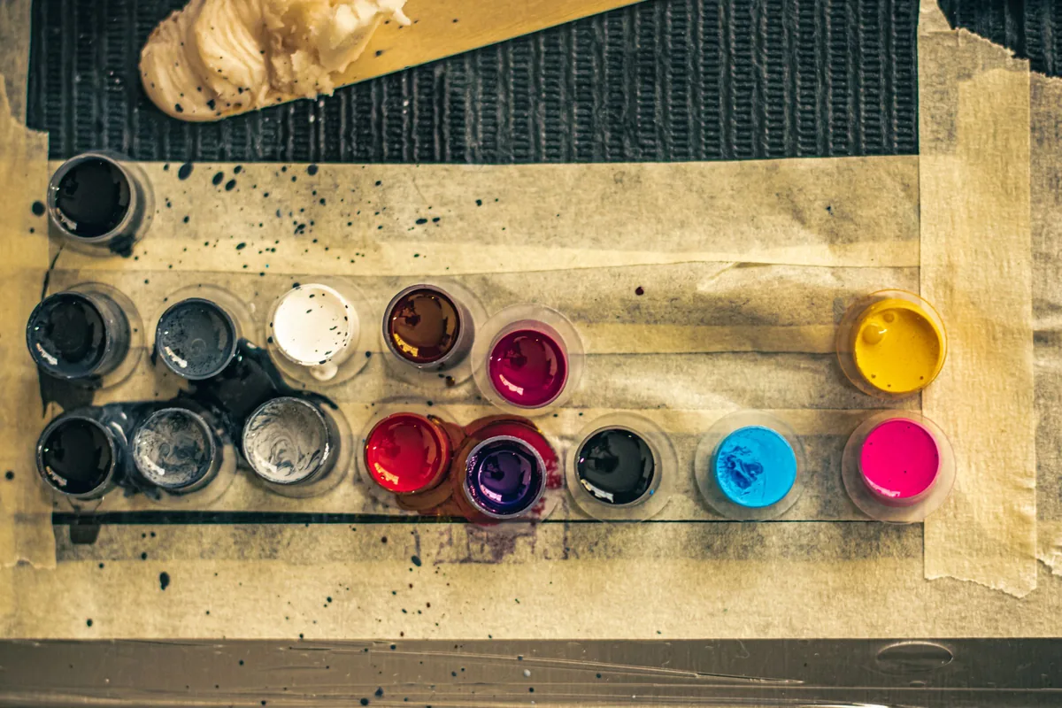 Ink caps filled with black and coloured ink on a taped workstation, the setup to look for at a tattoo studio in Kuantan