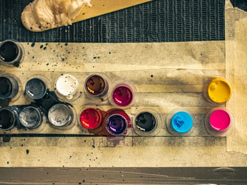 Ink caps filled with black and coloured tattoo ink on a taped workstation
