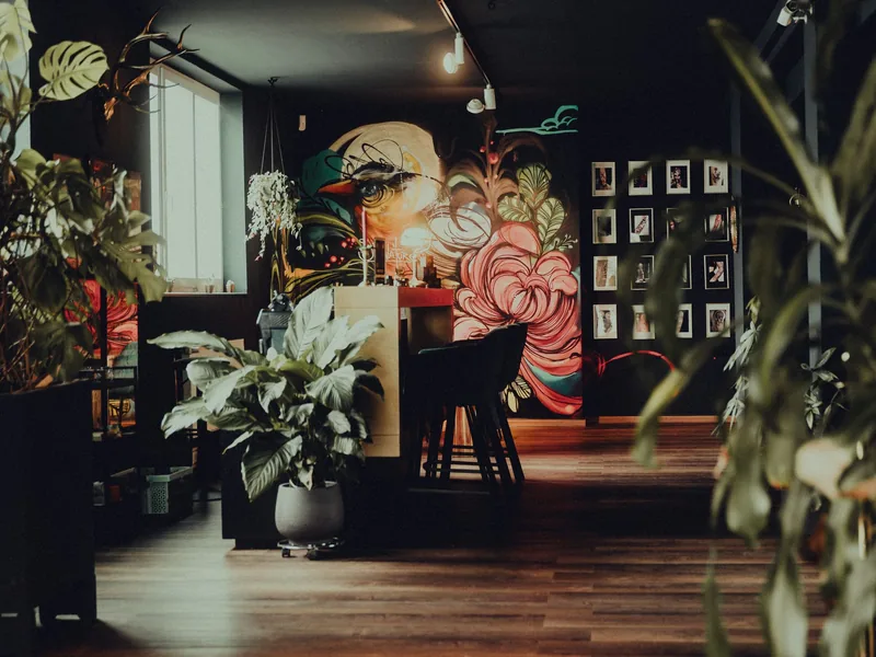 Tattoo parlour with a painted wall mural, plants and framed art