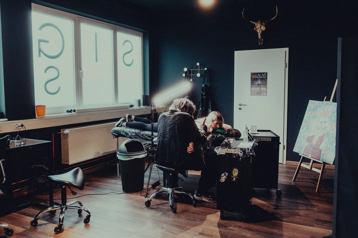 Tattoo session in progress in a spacious, dark-toned tattoo shop
