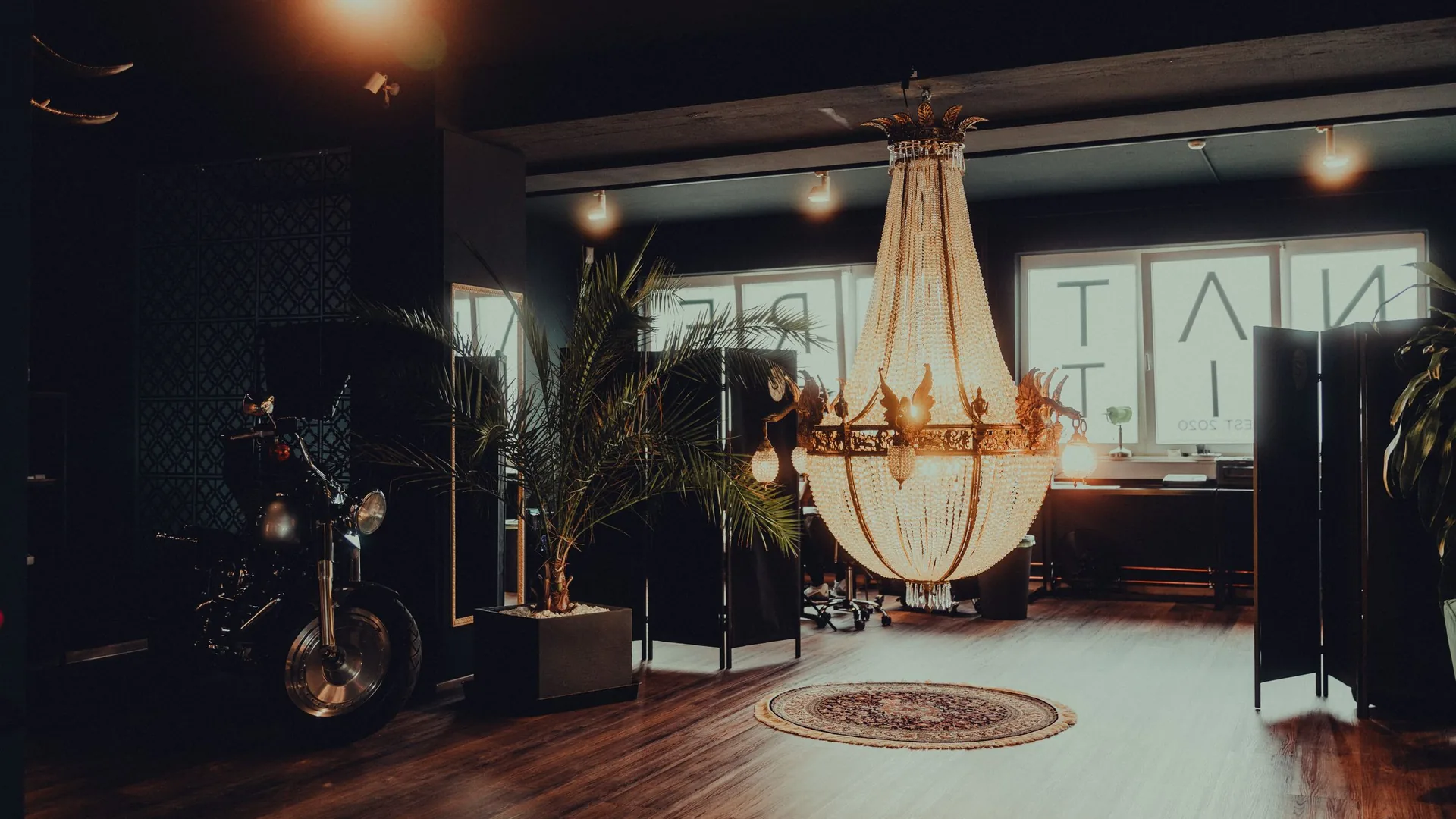 Spacious tattoo studio interior with a chandelier and wooden floor