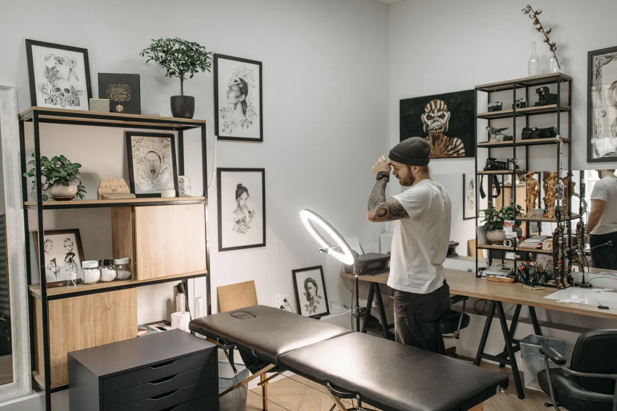 Bright, minimalist tattoo studio with a client bed and shelves of artwork